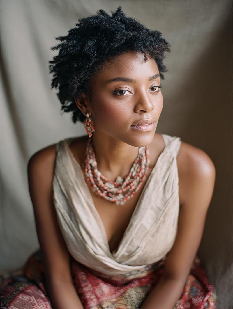 Editorial bridal portrait featuring a layered coral statement necklace and ivory silk wrap for a fine art luxury wedding